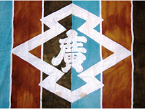 水色、茶色、黒の3色の縦じま模様で、中央のそろばんの珠のような形をした中に「廣」の文字が書かれている暖簾の写真