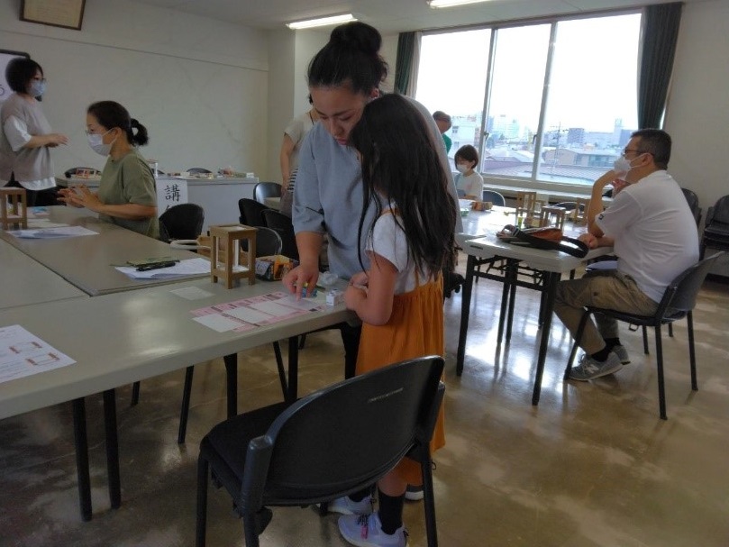 親子が行灯につける装飾を何にするか机に並べて選んでいる写真