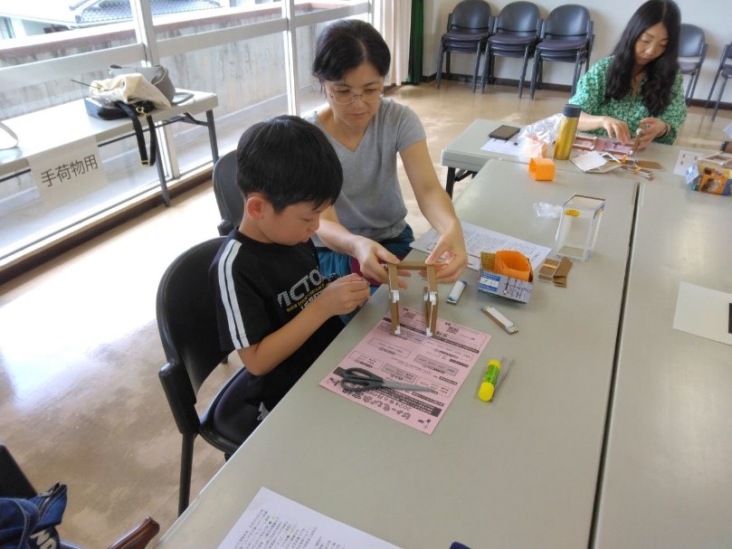 女性が男の子のサポートをしながら一緒に行灯を作っている様子を撮影している写真
