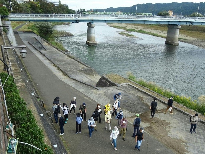 橋が架かる福島河岸の岸を歩く受講者たちを上から撮影した写真