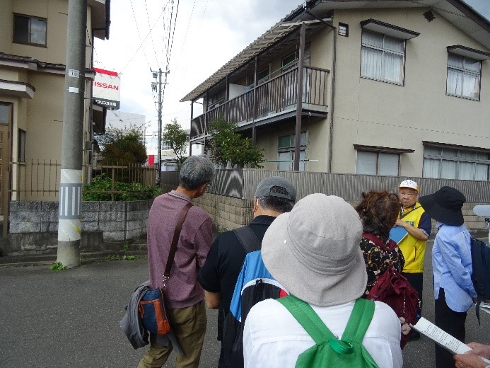 中村呉服店があった跡を現地まで行き講師から説明を受ける受講者たちを撮影した写真