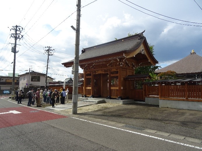 真浄院の入り口にある重厚感のある門の前で集まって話している受講者たちを撮影した写真