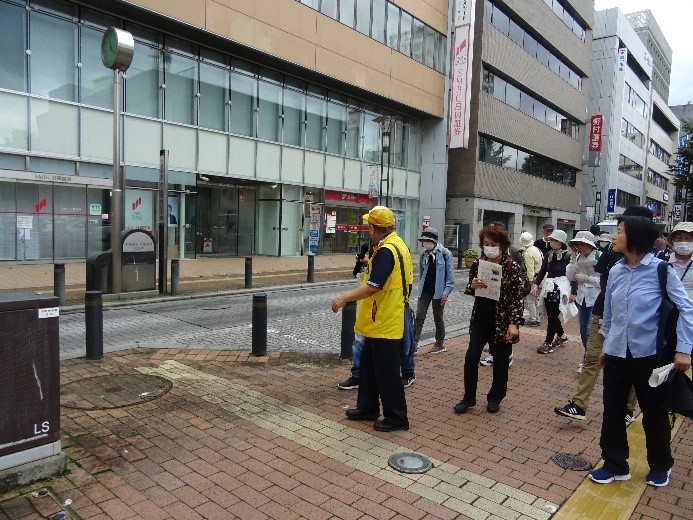 煉瓦で作られた道を歩いながら講師の説明を聞いている受講者たちを撮影した写真