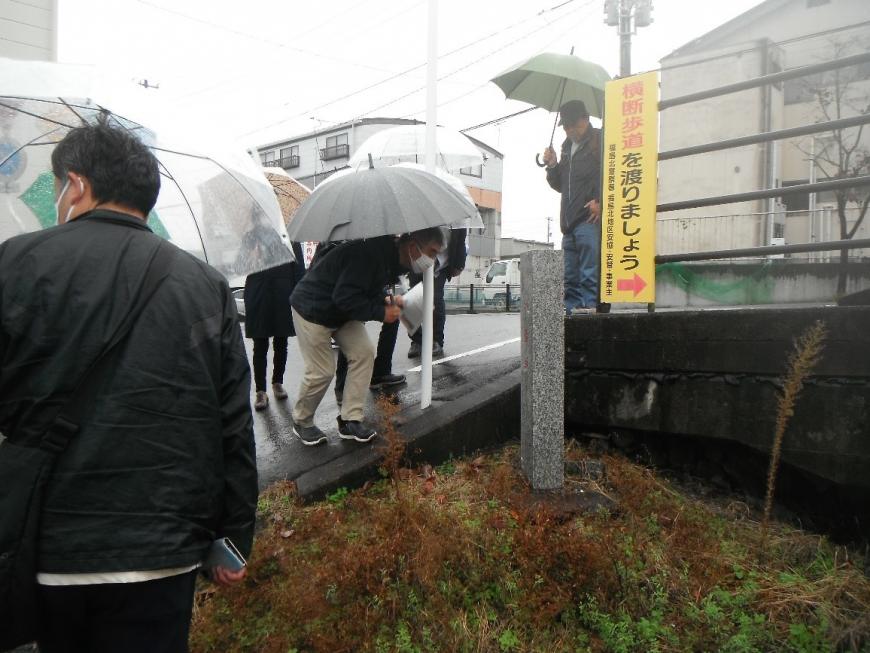 雨の降る中石柱に書かれた王貞治氏の直筆の文字を顔を近づけてみる受講者の写真