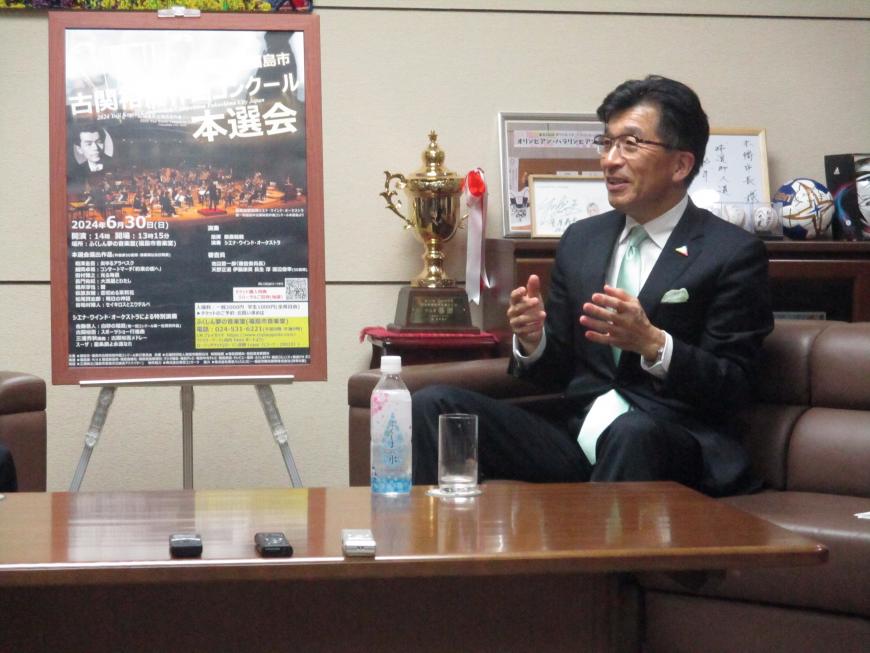 ソファーに座っている木幡浩市長が両手を使いながら話をしている様子の写真
