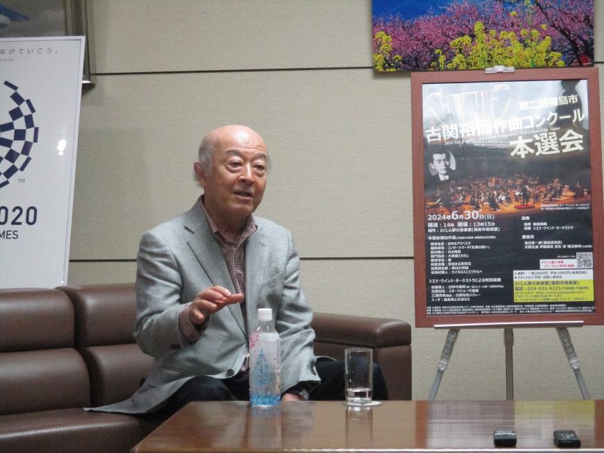 ソファーに座っている池辺晋一郎さんが手振りを交えて話をしている写真
