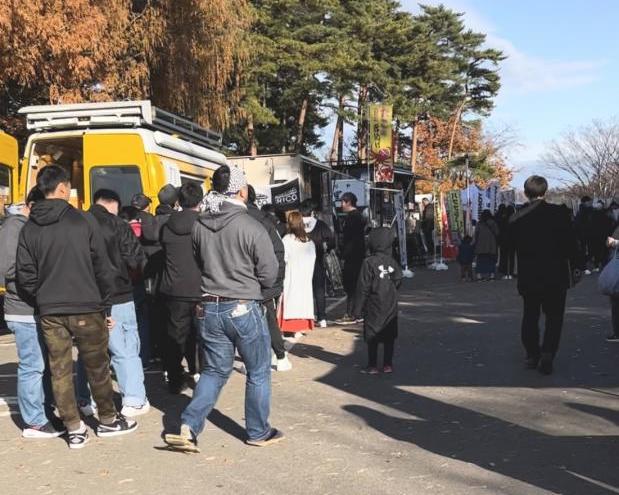 のぼり旗や、キッチンカーなどが並んでいるイベント会場の写真