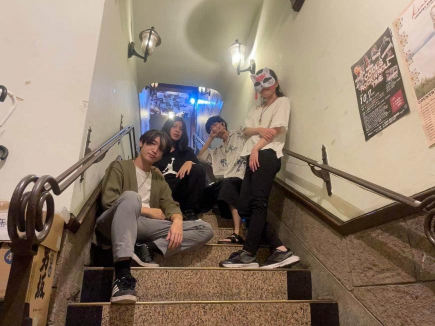 夜峰のメンバー3人が階段に座り、1人が立ったいるところを階段の下の方から撮影した写真