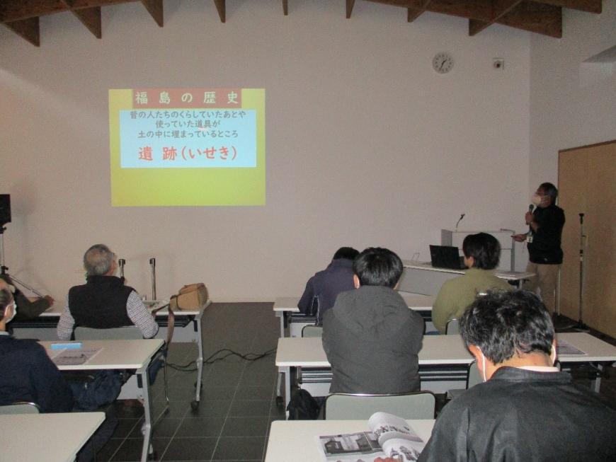 福島の歴史についてプロジェクターを使い講演をする講師と映像を見ながら聞く受講者の写真
