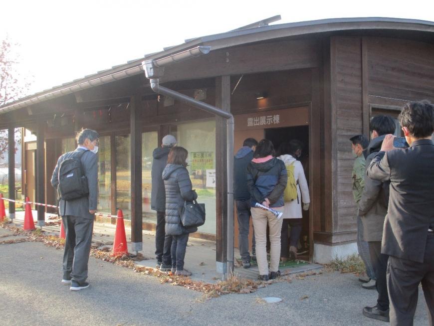 露出展示棟の中に入っていく受講者を後ろからスマホで撮っている男性を撮影した写真