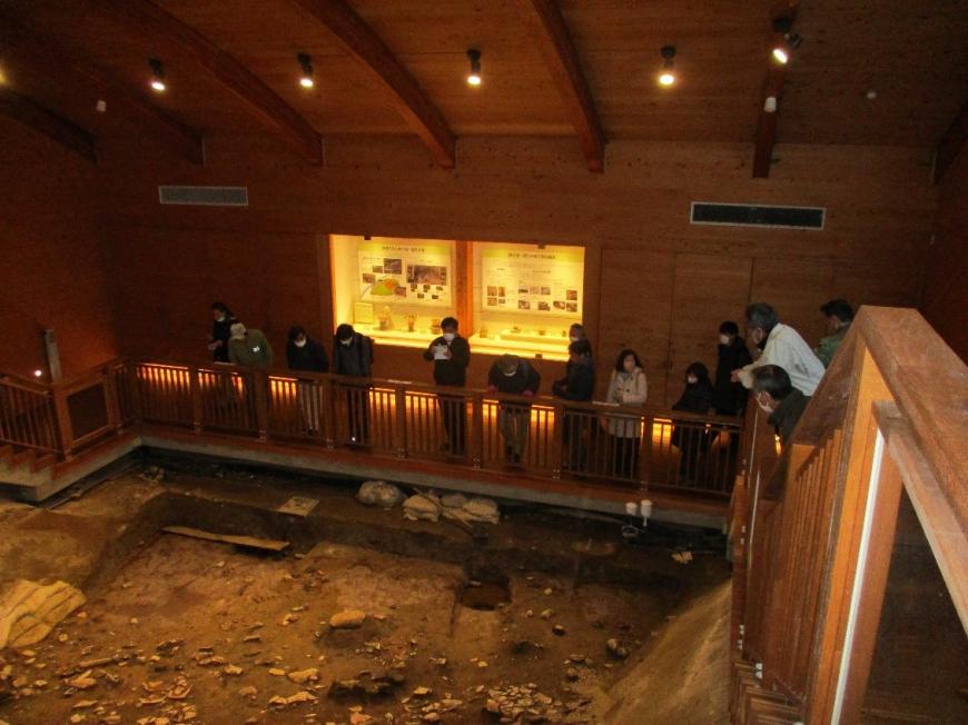 露出展示棟の中にある発掘調査跡を見ている受講者たちを撮影した写真