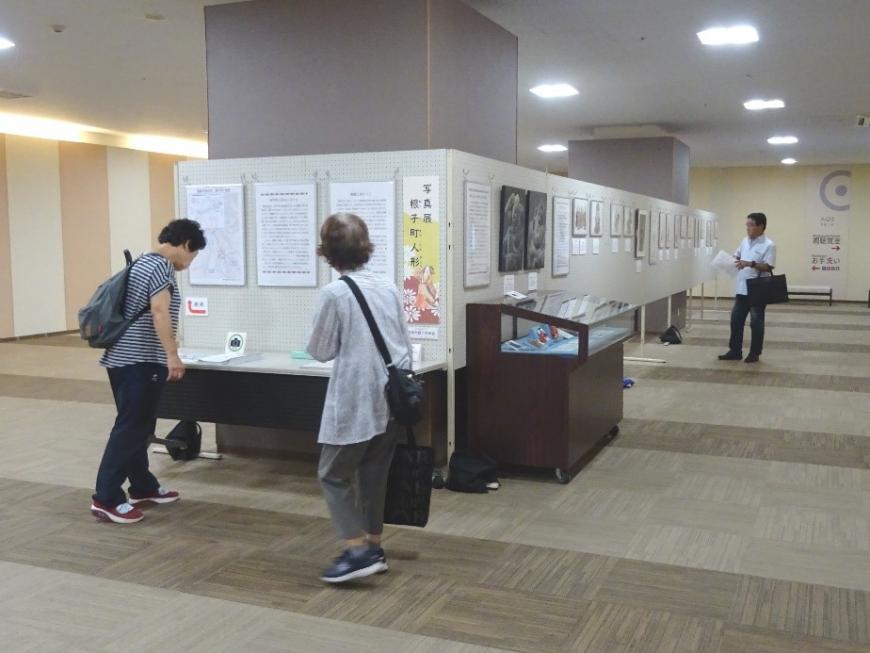 3名の方が広い室内の中央に展示されている資料をそれぞれ見ている写真