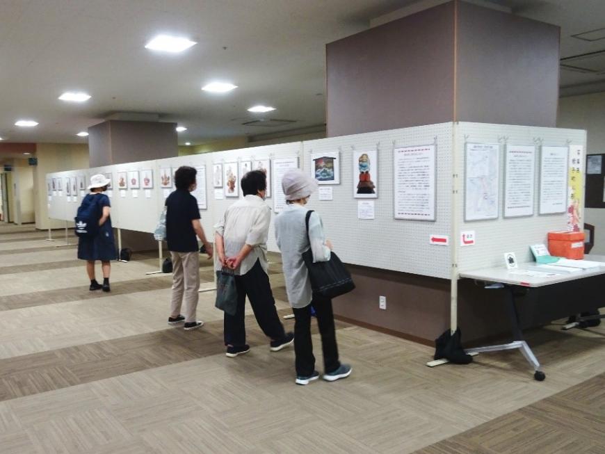 4名の方がそれぞれ立ち止まりパネルに展示されている資料を見ている写真
