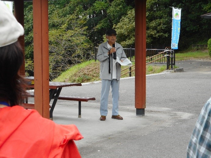 駒山公園のベンチ前で挨拶をする講師と話を聞く受講者たちの写真