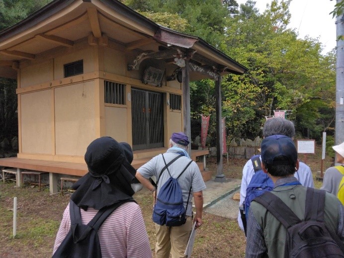 木の本来の色で造られた薬師堂前で観察する受講者たちを撮影した写真