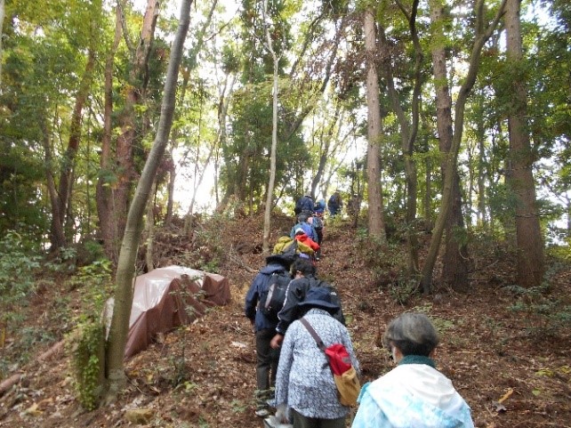 雷神碑と蛙石のある場所に向かうため傾斜のある山道を並んで進む受講者たちを撮影した写真