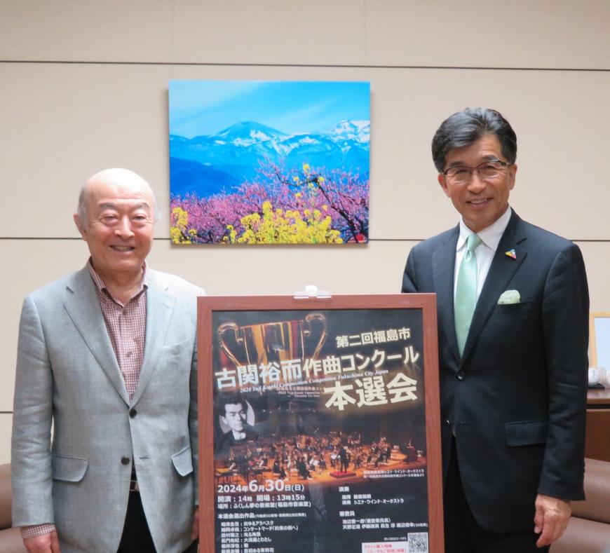第二回福島市古関裕而作曲コンクール本選会のポスターの左側に池辺晋一郎さん、右側に木幡浩市長が立ち、記念撮影をしている写真