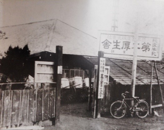 純良牛乳 第二厚生舎と書かれた看板があり、門の奥に建物がある第二厚生舎外観の白黒写真