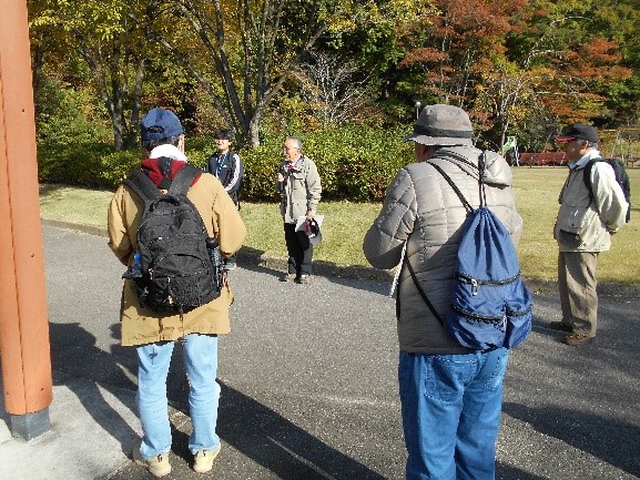 駒山公園前でフィールドワークの為集まった受講者たちと説明する講師を撮影した写真