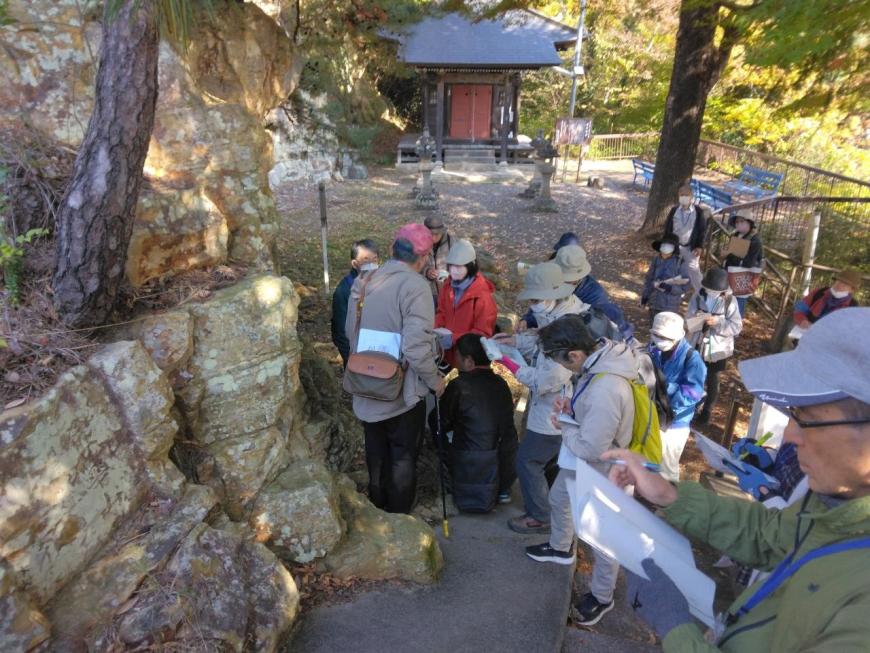 岩谷観音磨崖仏付近にある苔の生えた岩を調べている講師と受講者たちを撮影した写真