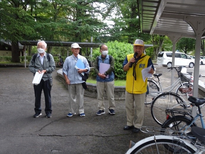 4人の講師の中の黄色い服を着た講師の男性がマイクを持ち説明している写真
