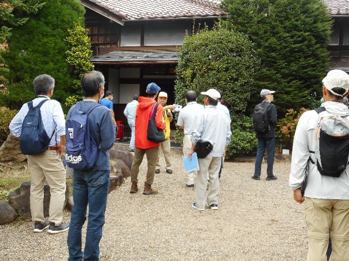 砂利が敷かれ整備された御倉邸の庭先を歩いて回る受講者たちと講師の写真