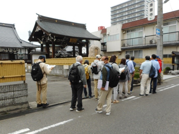 大きな康善寺の門を目印に歩いていく受講者たちの写真