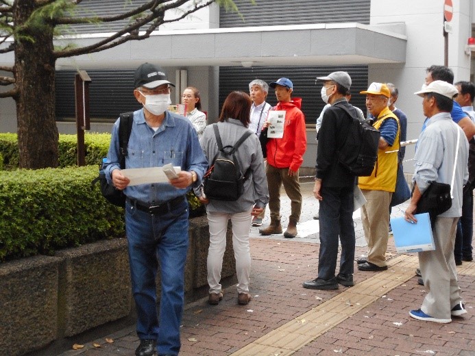 米沢口(庭坂口)跡にある説明板を読みながら詳しい説明をする講師と話を聞く受講者たちの写真