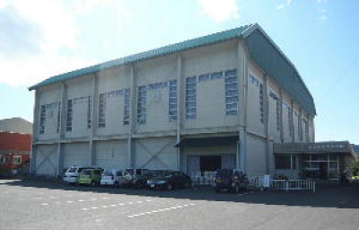 駐車場のすぐ横に建っているエメラルドグリーン色の屋根をした東部体育館の外観写真