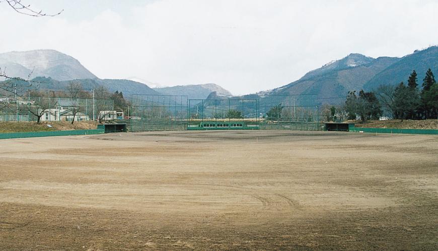 奥に山々が見えている広々とした飯坂野球場の写真