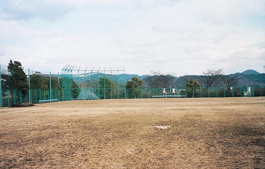 芝生が広がる広場の周囲を緑色のフェンスが囲んでいる広々とした蓬莱中央公園の写真