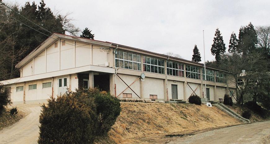 少し高い場所に建っている三角屋根の松川地区体育館の外観写真