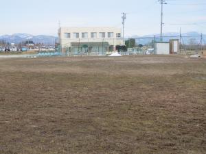 白い長方形をした建物の前に広がっている上鳥渡地区運動場の写真