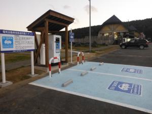 電気自動車用急速充電器の案内看板と充電設備、2台分の駐車スペースの写真