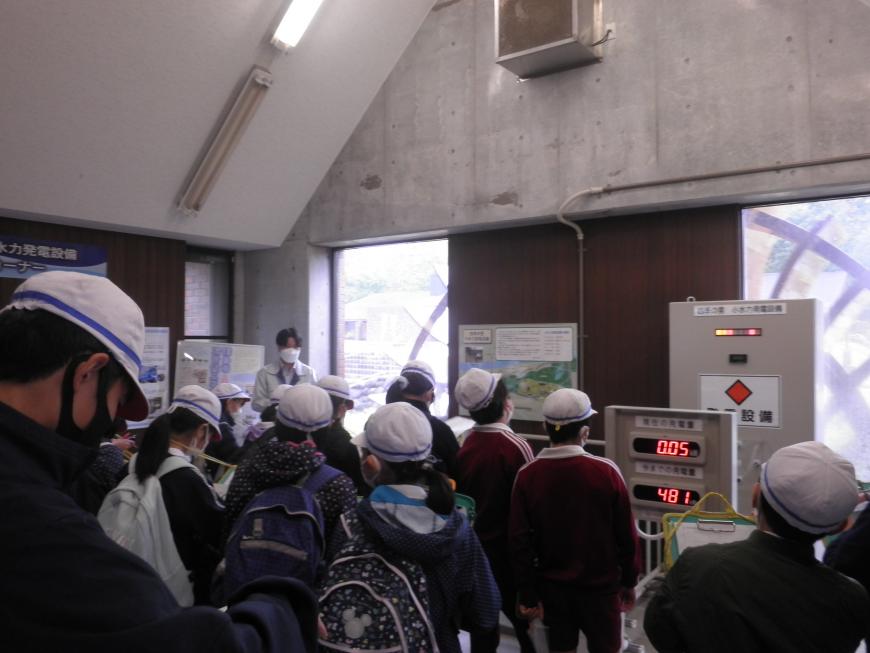 小水力発電設備の機械を見学している子供たちの写真