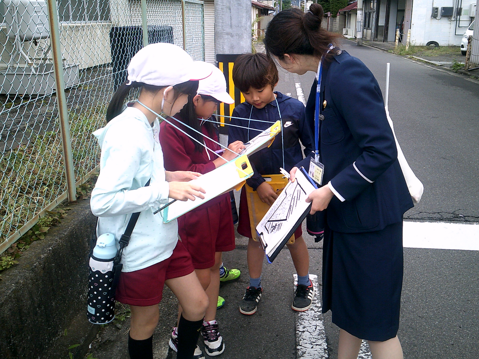 小学生の男女と一緒にぼうさい探検をしている女性の写真