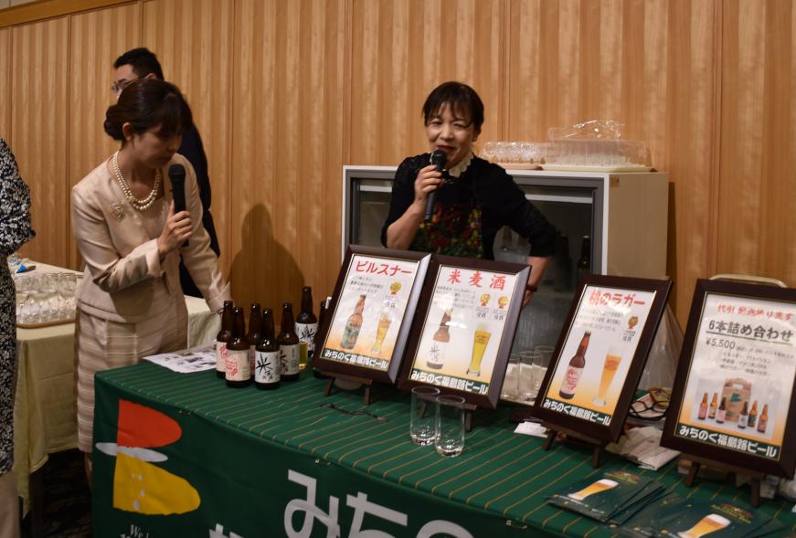 並べられたビールの瓶、額縁に入った地ビールのチラシ、グラスに注がれたビールの写真が載ったパンフレットなどが置かれている吾妻山麓ふく酒街道のブースを写した写真