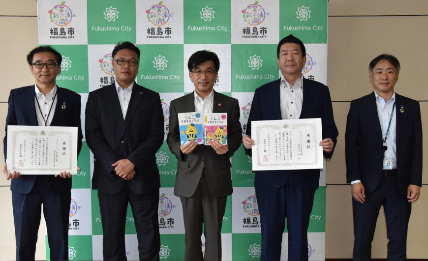 あいおいニッセイ同和損害保険株式会社の関係者が2人ずつ真ん中の市長の隣に並び、「交通安全ドリル」と賞状を持ちながら記念写真をしている寄贈式の写真