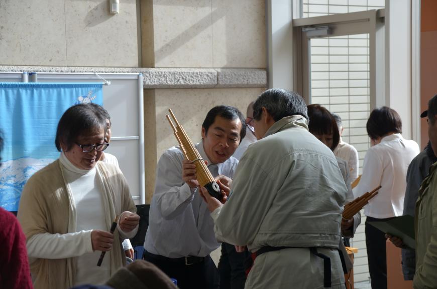 演奏者の男性が来場者の男性に雅楽の楽器の説明をしている写真