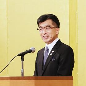 演台に置かれたマイクの前に立って市長が近況説明をしている写真