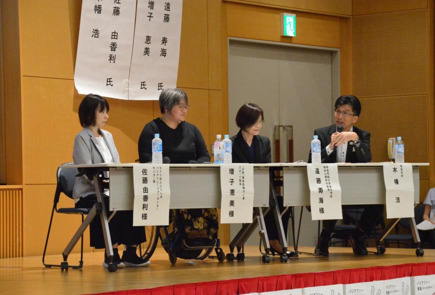 長テーブルの前に市長を含め4名が着席しており、市長がマイクを持って3名に向かって話をしている様子の写真