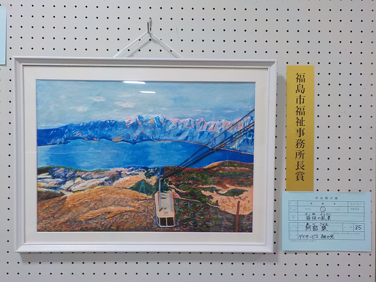 山に囲まれた湖やロープウェイが上がってくる様子を高台から描いた福島市福祉事務所長賞受賞作品の写真