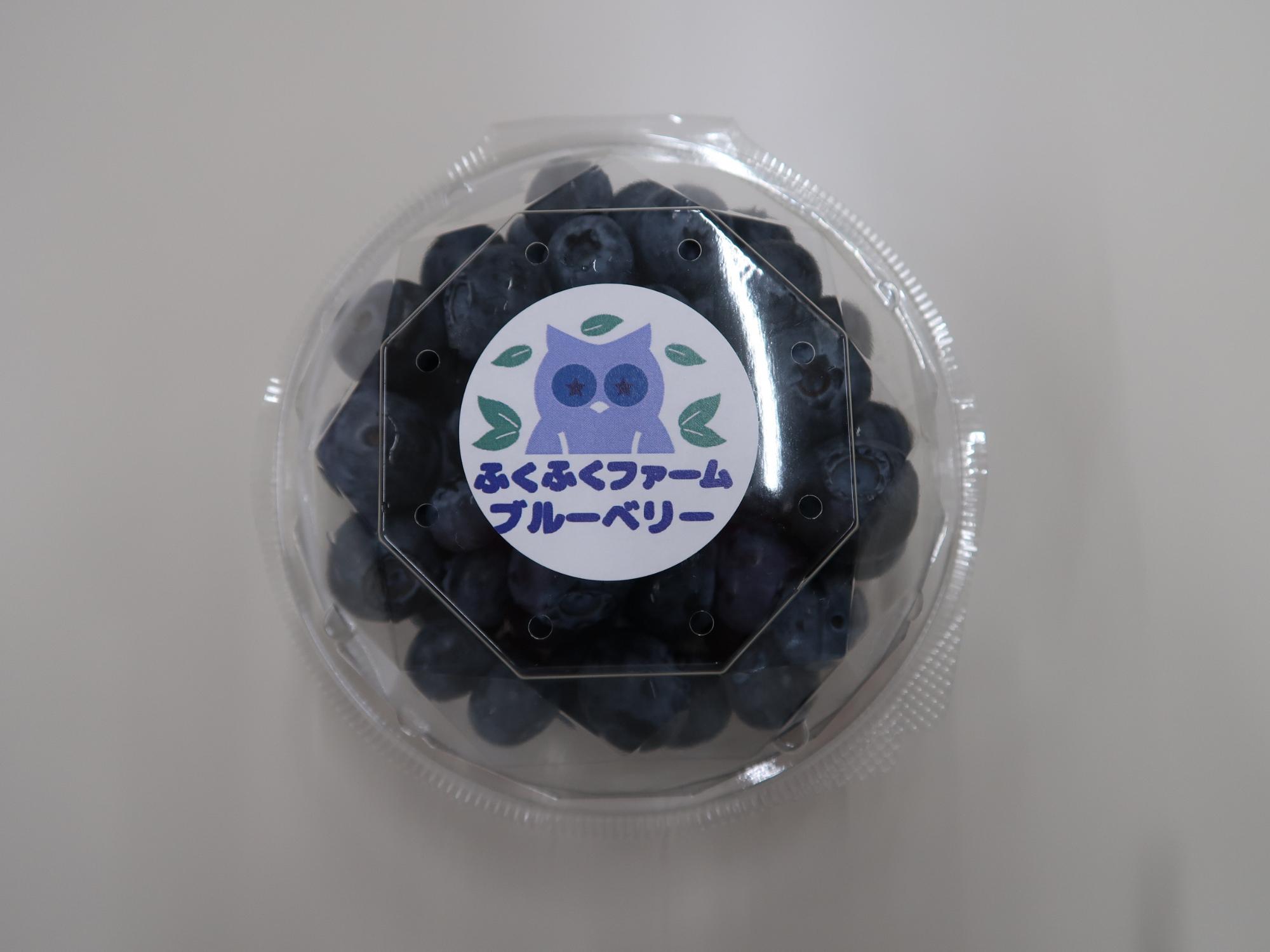 透明の容器の中央に「ふくふくファームブルーベリー」と書かれたラベルが貼られたブルーベリーの商品の写真