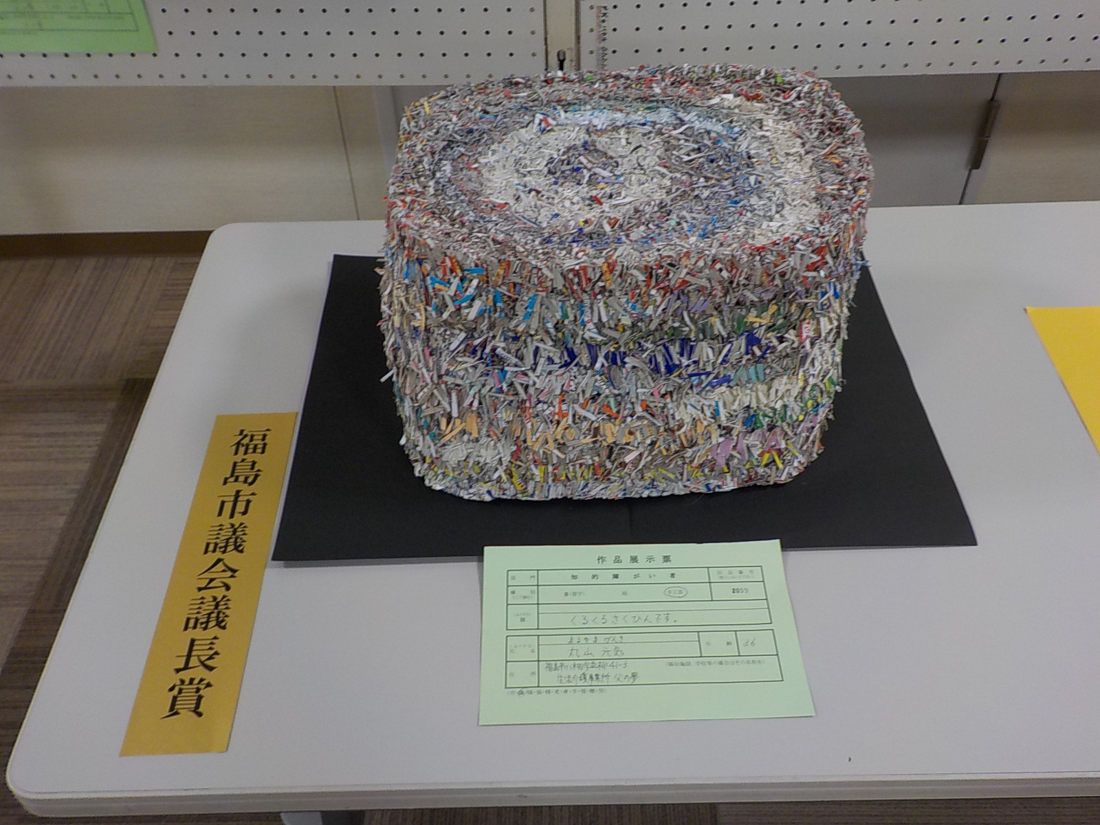 カラフルな色の帯びが付いた物が渦巻き状に巻かれている福島市議会議長賞受賞作品の写真