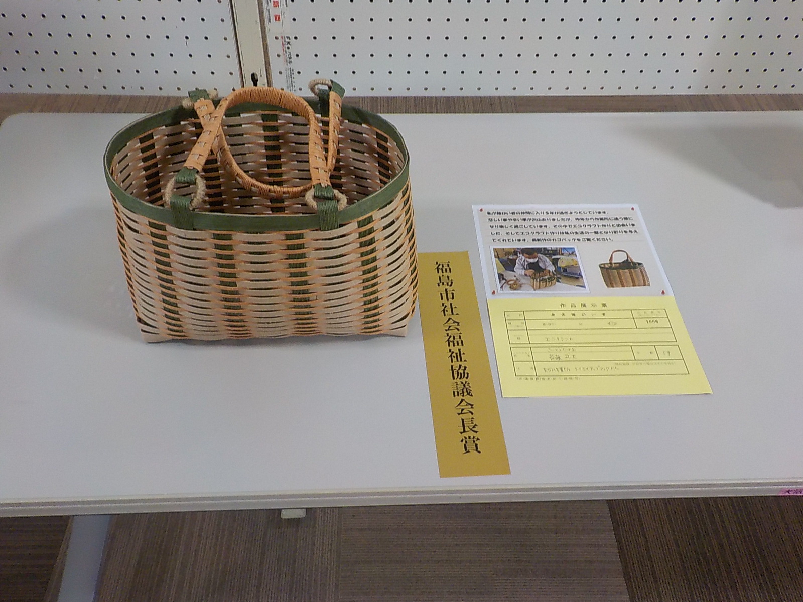 ベージュと緑色のクラフトバンドで作成したカゴが展示された福島市社会福祉協議会長賞受賞作品の写真