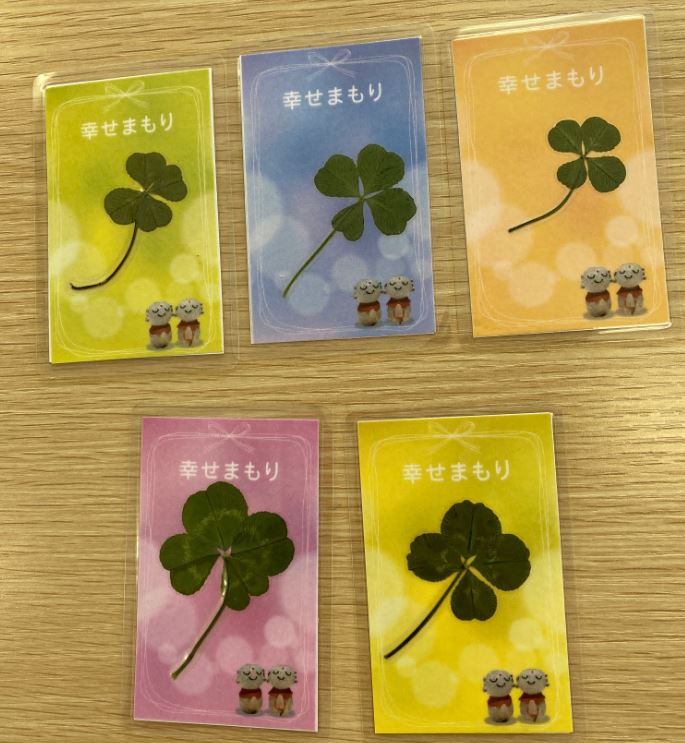 大きさがバラバラな四つ葉のクローバーが入った5つの幸せまもりの写真