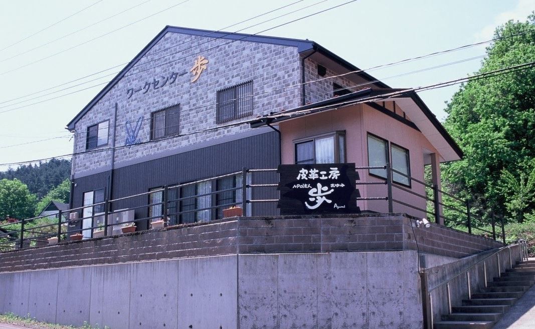 2階建てのレンガ調の外壁に「ワークセンター歩」と事業所名が書かれた建物外観の写真