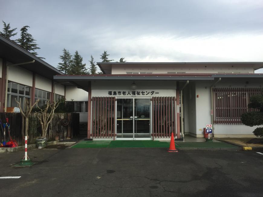 入り口上に「福島市老人福祉センター」と書かれた2階建てで白壁の建物外観の写真