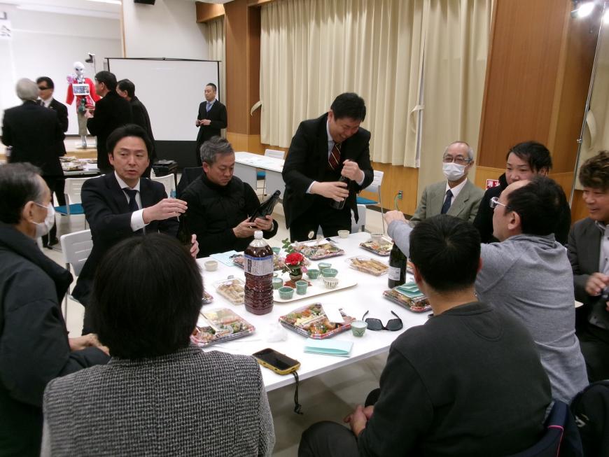 テーブルに食事が並べられ食事を楽しむ参加者達の写真