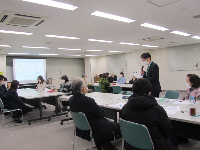 男性が立って手元に資料を持って説明をするのを参加者達が聞いている写真